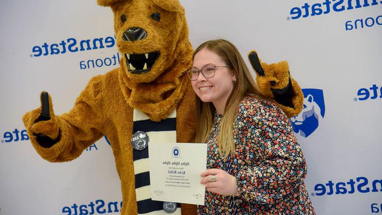 Psychology major Kylee Rishel poses with her certificate 和 the Nittany Lion after the induction ceremony. 